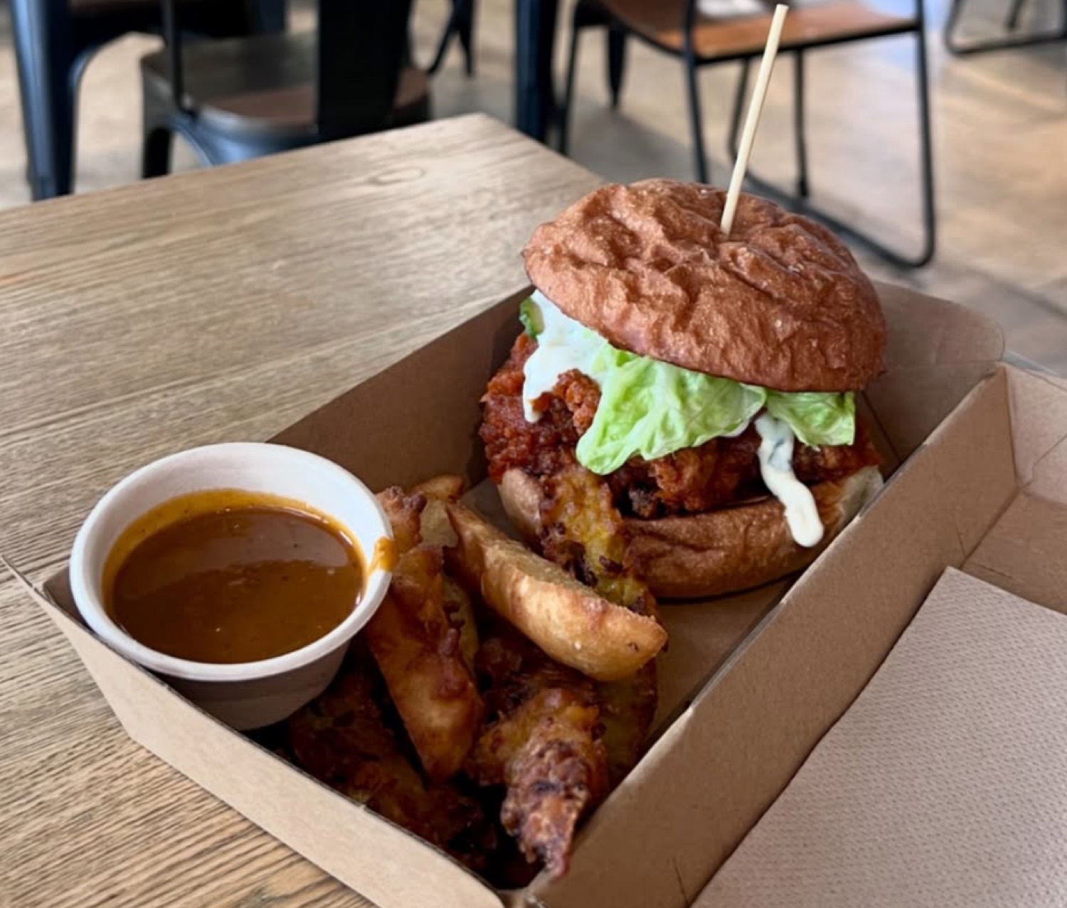 Fried chicken burger with wedges and curry sauce in a takeaway box