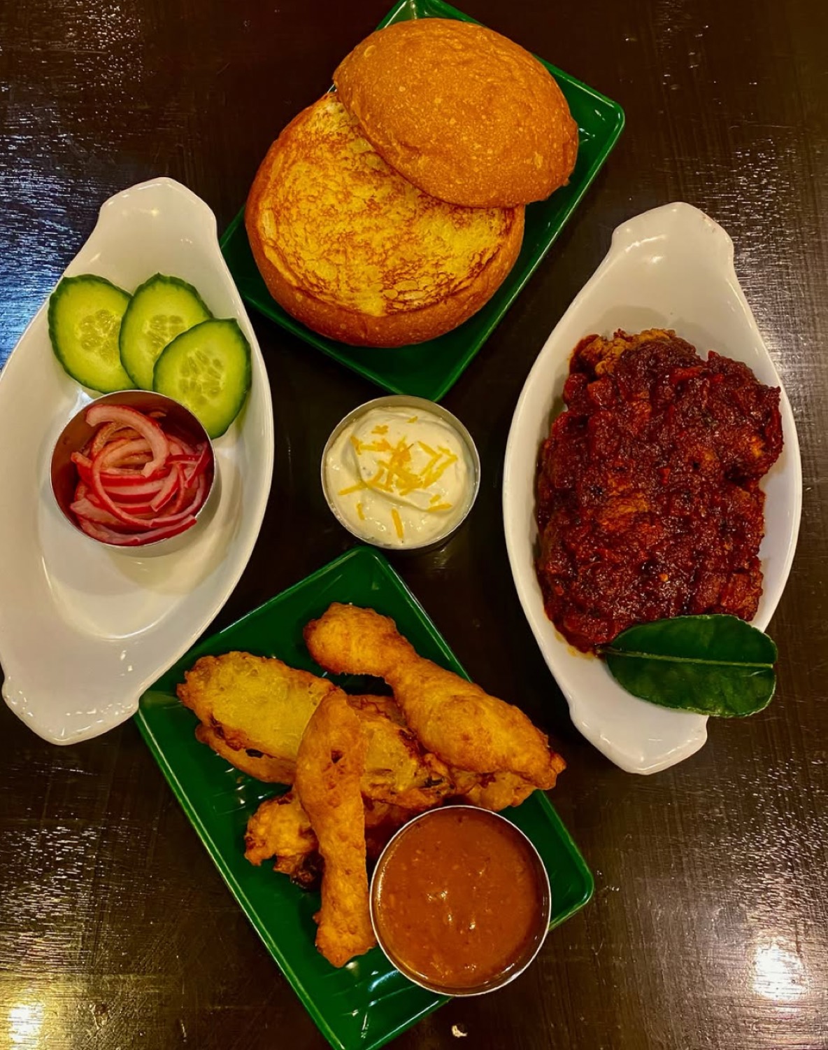 Flat lay of buns, rendang, pickled onion, raita and fried chicken